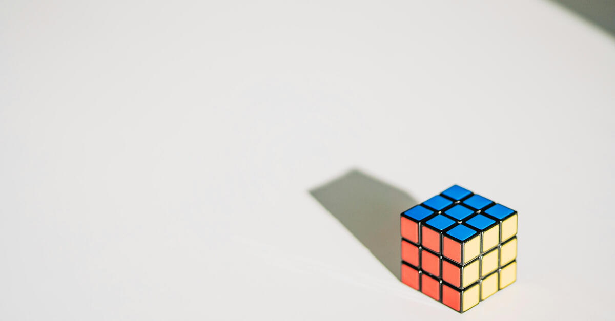 A colorful, unsolved Rubik’s cube resting on bright green bamboo leaves, symbolizing complexity, adaptability, and the hidden structure beneath chaos.