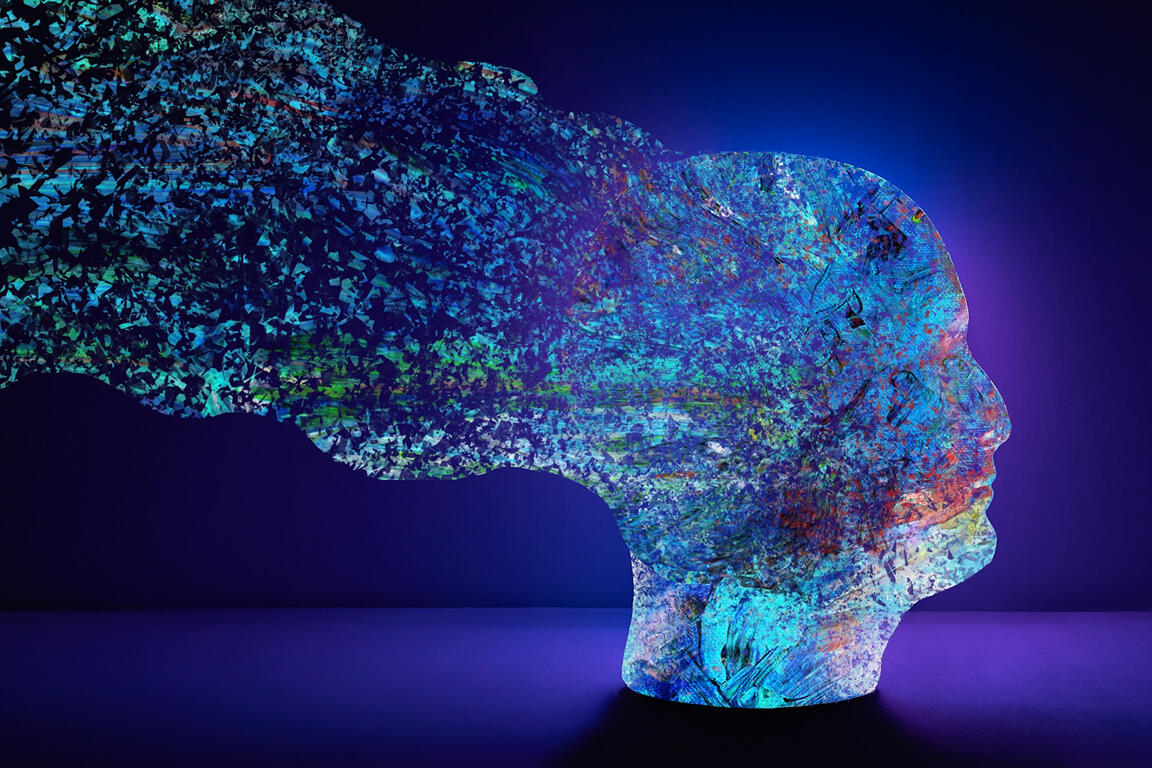 Interfaces don’t just display data — they absorb us, too. A colorful human head made of mosaic-like fragments dissolves into streaks of digital light against a deep blue background.