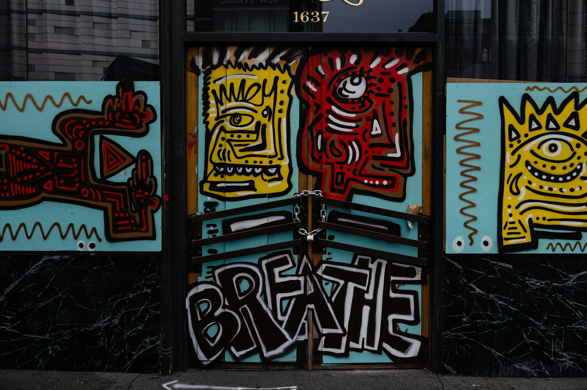 A minimalist scene of two small round tables surrounded by several wooden chairs in an empty room with a plain white wall. One chair is slightly apart from the group, creating a quiet, contemplative sense of absence.