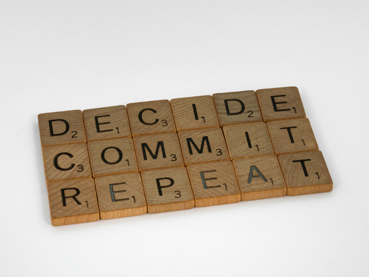 Decide. Commit. Repeat. Scrabble tiles spelling “Decide. Commit. Repeat.” — a visual rhythm of discipline and quiet persistence.