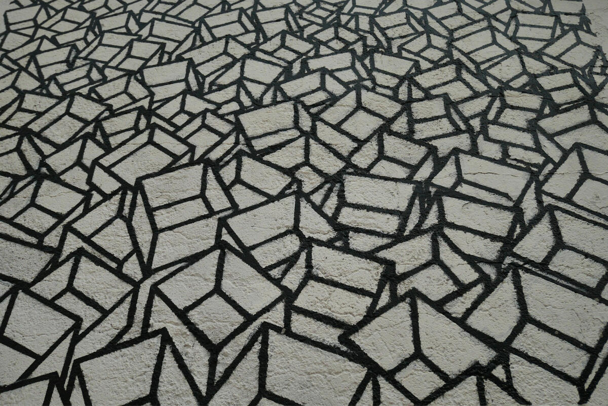 Abstract black geometric pattern on a light concrete surface, showing interlocking cubes that evoke networks, decentralization, and distributed systems.