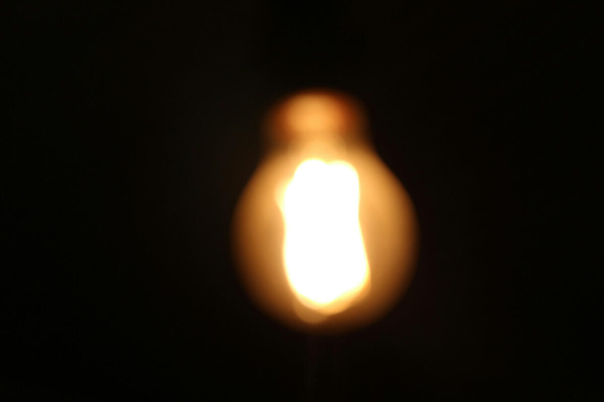 Blurred lightbulb A softly blurred glowing lightbulb against a dark background, symbolizing creative spark, persistence, and the glow of unseen effort.