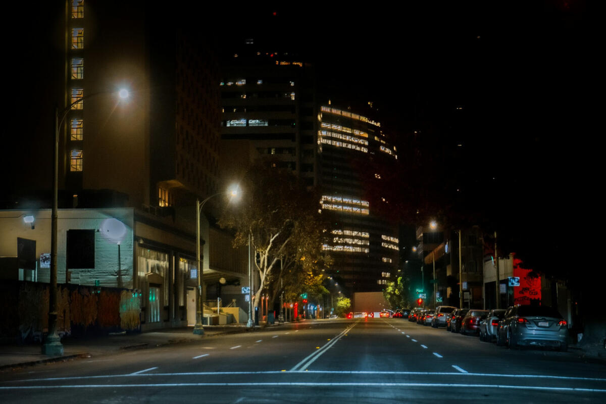 Walking Through the In-Between Empty city street at night in downtown Oakland, buildings glowing with scattered window lights, capturing the feeling of moving through a quiet, uncertain chapter.
